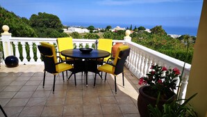 A terrace with a round table and chairs, a potted plant, and a view of the sea and hills. - Studio Apartment "Roca Penthouse"no kids under 10 year, with Sea View, Shared Pool & Wi-Fi (Estepona)