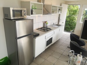A compact kitchen with a refrigerator, microwave, stove, and sink.
