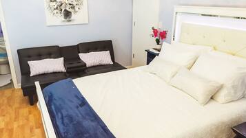 A bedroom with a bed, a nightstand, a wall-mounted lamp, and a door.