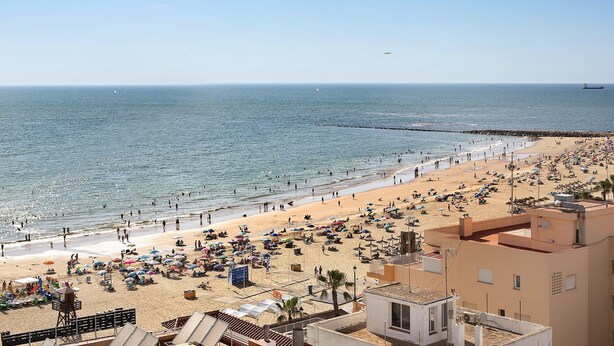 Ein Strand mit Blick auf das Meer, einem Rettungsturm und Strandliegen.