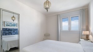 Ein Schlafzimmer mit einem Bett, einem großen Spiegel, einem Fenster und einer Wandleuchte.