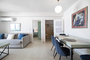 Un salon moderne avec un canapé, une table à manger, des chaises et un tableau accroché au mur.
