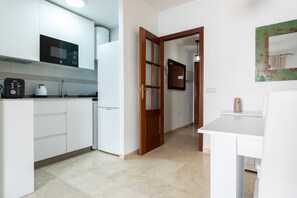 A modern kitchen with white cabinets, a built-in microwave, and a coffee maker.
