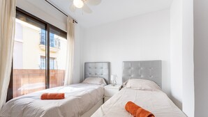 A hotel room with two beds, a balcony, and a ceiling fan. - 'City in Fuengirola Centro' Apartment with Balcony and Wi-Fi (Fuengirola)