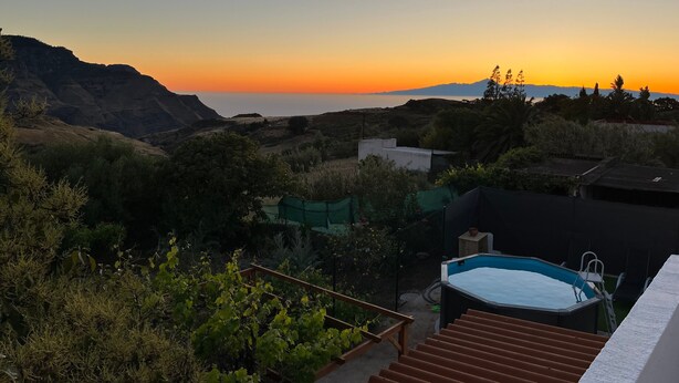 Ein Pool, eine Treppe und ein Blick auf den Sonnenuntergang über einer Berglandschaft.