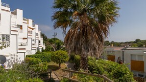 Zona residencial con edificios blancos, una palmera y un camino.