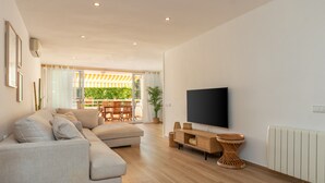 Una sala de estar moderna con sofá, televisor y suelo de madera.