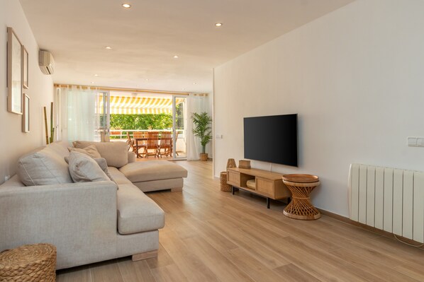 A modern living room with a sofa, TV, and wooden flooring.