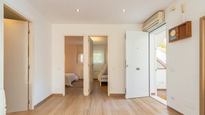 Un pasillo con suelo de madera, paredes blancas y una escalera que sube a otra habitación.