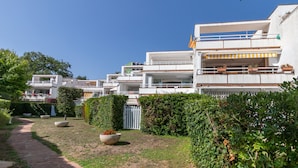 Un edificio residencial moderno con varios balcones, un sendero y un jardín bien cuidado.