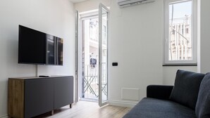A modern living room with a flat-screen TV, a grey sofa, and a wooden cabinet. - Via Niccol Tommaseo 4 - Appartamento 4 (Naples)