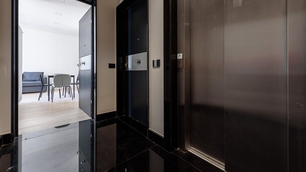 A modern hallway with a glass door leading to a room with a sofa and chairs. - Via Niccol Tommaseo 4 - Appartamento 4 (Naples)