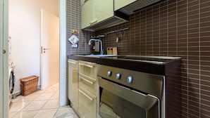 Uma cozinha compacta com forno embutido, micro-ondas e pia.