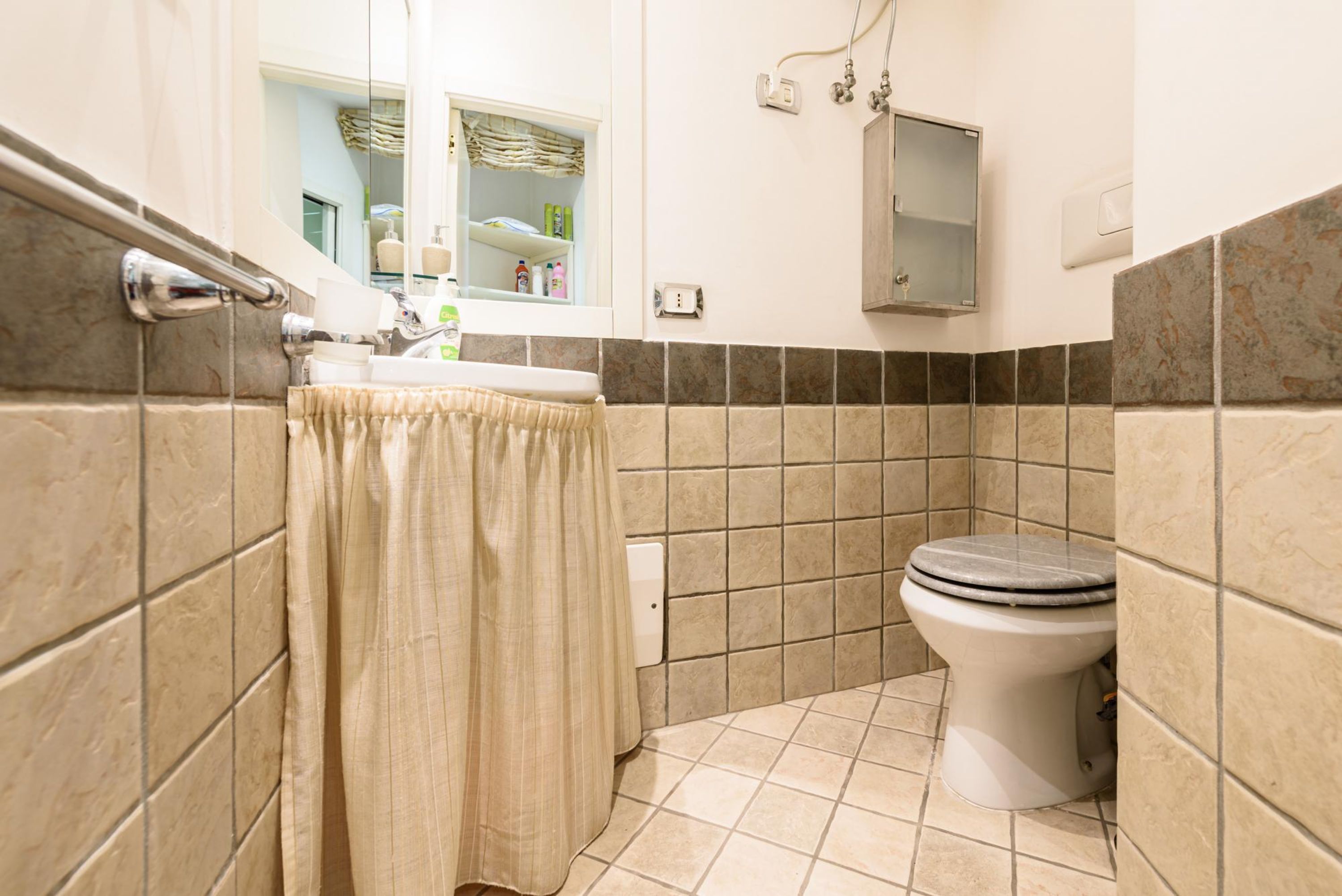 A bathroom with a toilet, sink, and mirror.