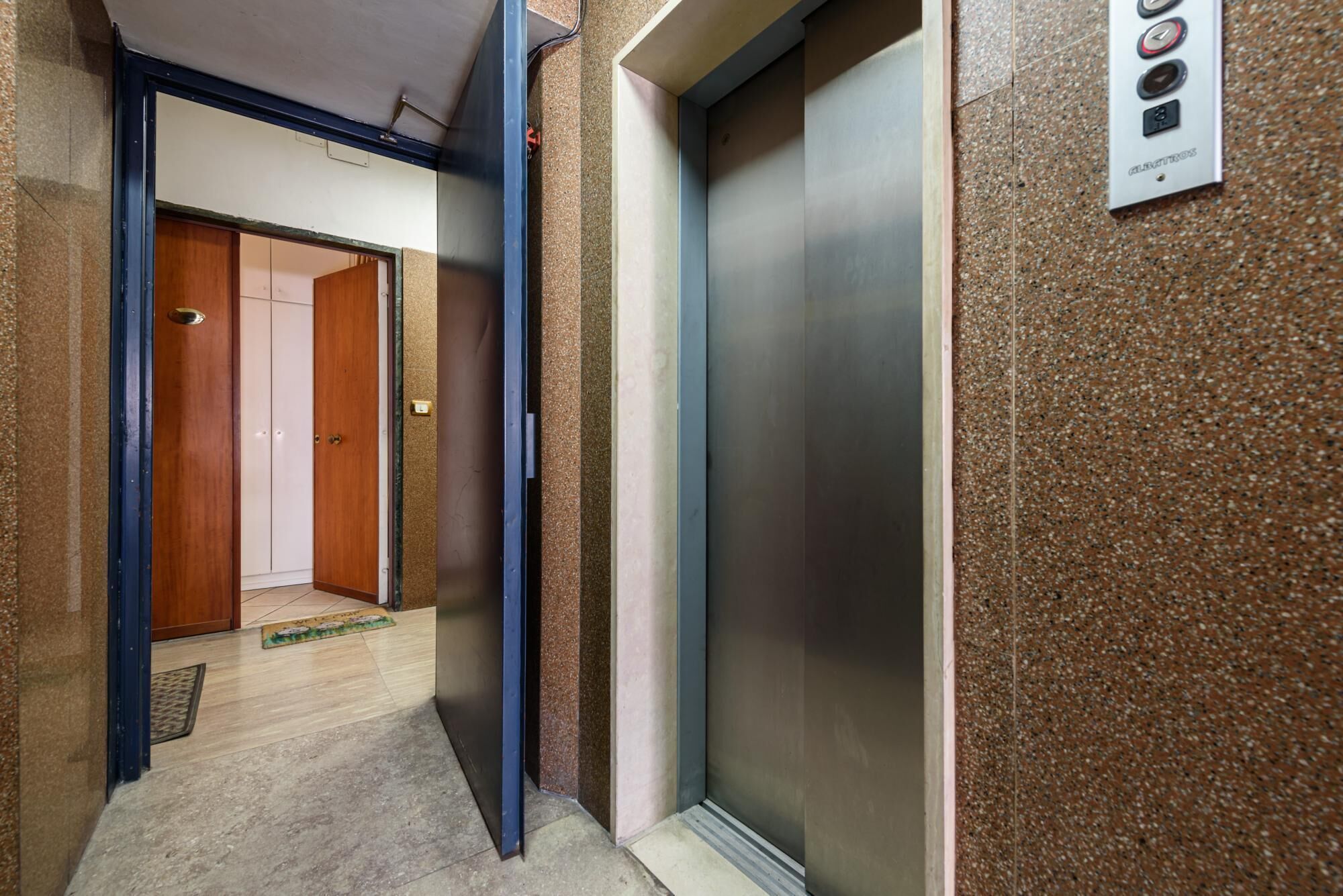 An elevator in a hallway with a door leading to a room.