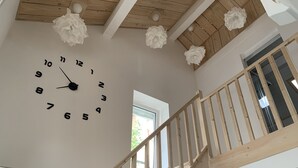 A staircase with wooden railings and a white wall with a large clock. - Le Majol , Gîte Rural au Coeur du Jura (La Chapelle-sur-Furieuse)