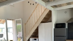 A modern kitchen with a wooden table and chairs, a built-in oven, and a microwave. - Le Majol , Gîte Rural au Coeur du Jura (La Chapelle-sur-Furieuse)