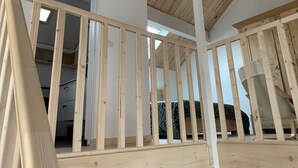 A room with a wooden ceiling and a sloped roof, visible beams, and a bed with green patterned bedding. - Le Majol , Gîte Rural au Coeur du Jura (La Chapelle-sur-Furieuse)