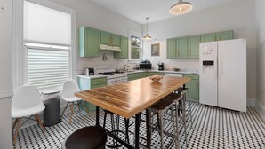 Una cucina moderna con mobili verdi, un tavolo di legno e un frigorifero bianco.