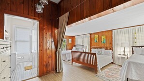 Camera da letto con rivestimento in legno, due letti, una cassettiera e un armadio a muro.