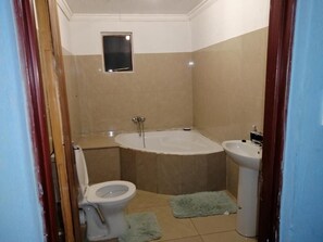 A bathroom with a bathtub, toilet, and sink. - Moholoholo lodge  (Bushbuckridge)