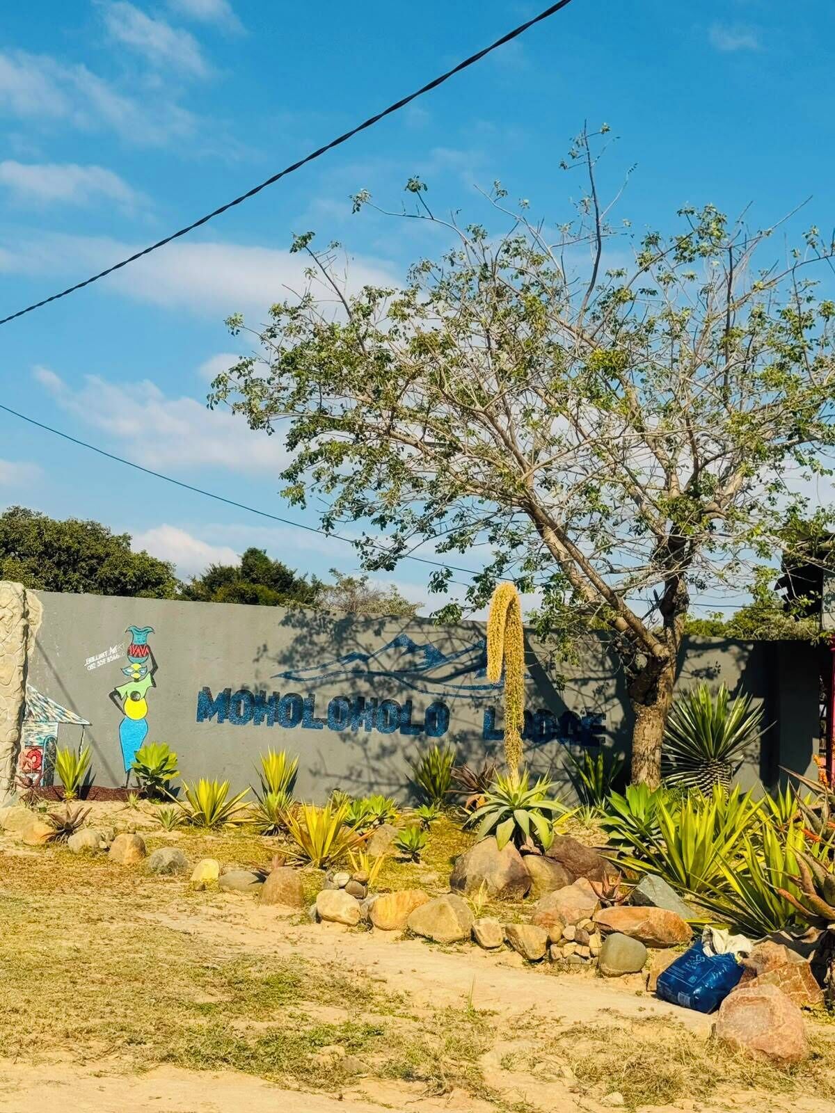 A sign with 'MOHOLOLO LODGE' and a mural of a woman.