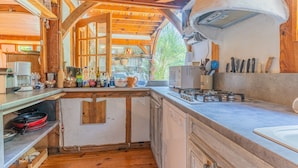 A rustic kitchen with wooden beams, a gas stove, and various kitchen utensils.
