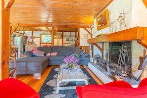 Una sala de estar acogedora con chimenea, vigas de madera, un sofá y una mesa de centro.