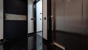 A hallway with a black door, a mirrored wall, and an elevator. - Via Niccol Tommaseo 4 - Appartamento 5 (Naples)