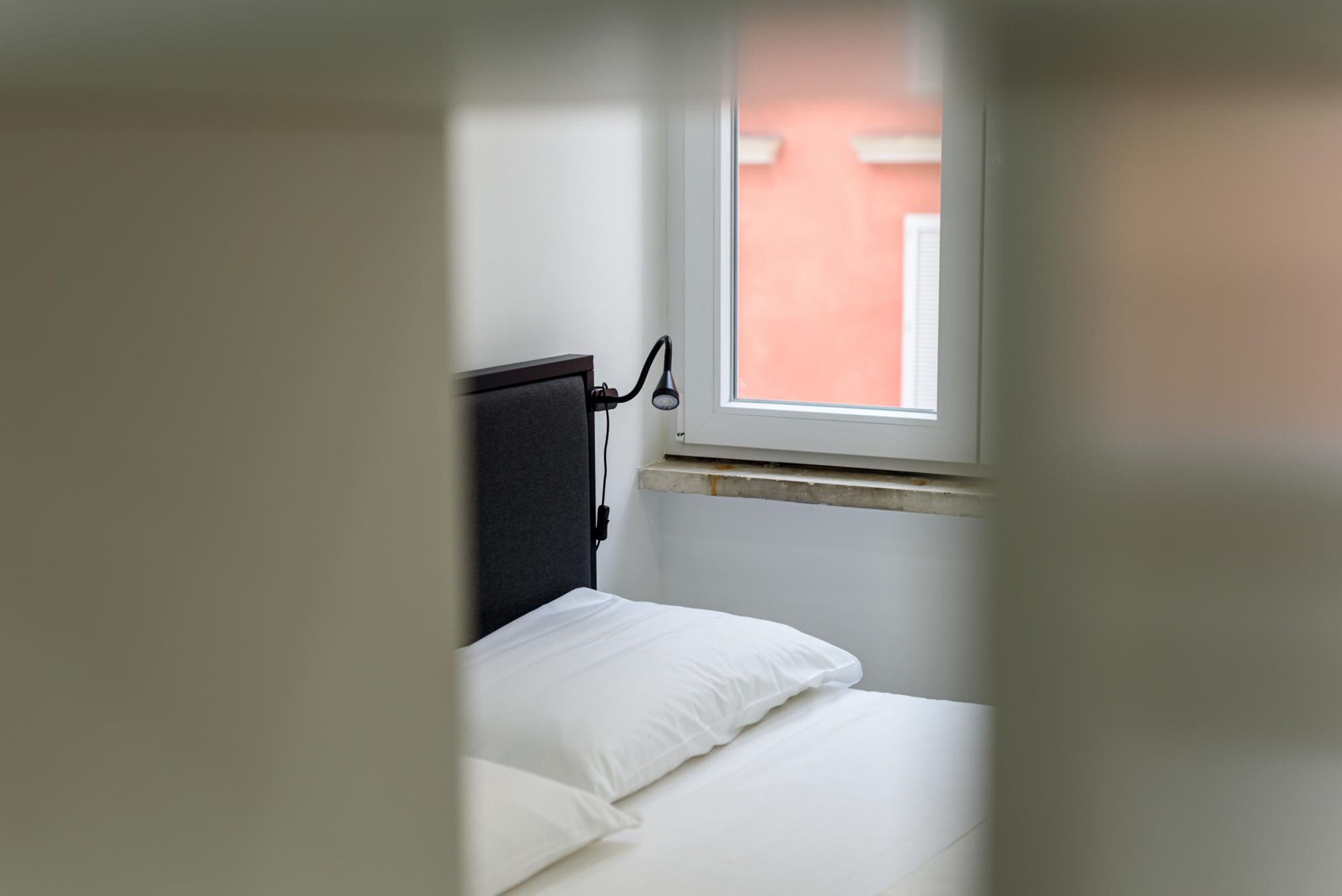 Een kamer met een bed, een raam en een lamp aan de muur.