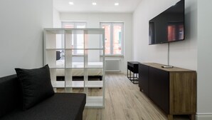 A modern, well-lit room with a bed, a TV mounted on the wall, and a wooden cabinet. - Via Niccol Tommaseo 4 - Appartamento 5 (Naples)
