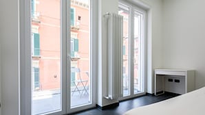 A hotel room with a large sliding glass door leading to a balcony, a white desk, and a bed. - Via Niccol Tommaseo 4 - Appartamento 6 (Naples)
