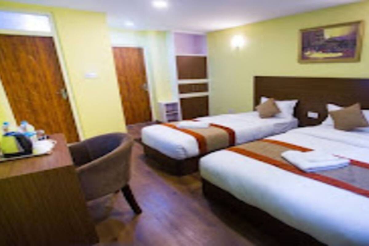 A hotel room with two beds, a desk, and a chair.