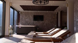 A spa room with massage chairs, a sauna, and a stone wall. - Bellezza Resort & SPA (Morinj)