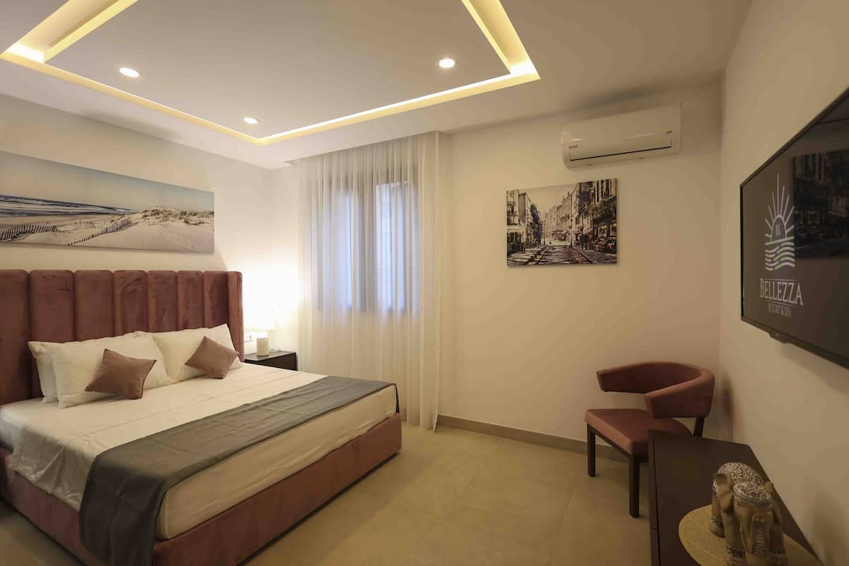 Une chambre d’hôtel moderne, dotée d’un grand lit, d’un bureau, d’une chaise et d’œuvres d’art accrochées aux murs.