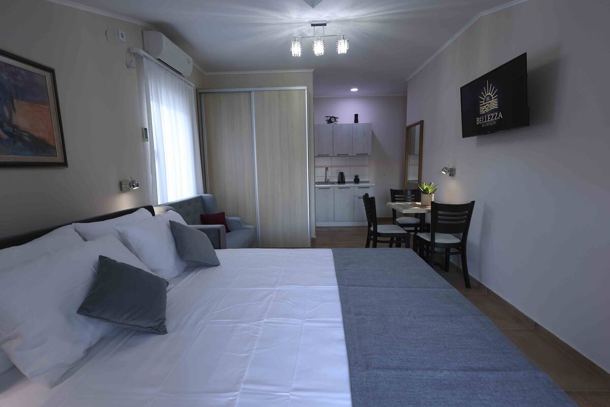 Une chambre d’hôtel équipée d’un lit, d’un bureau, d’une chaise, d’une table à manger et d’un téléviseur fixé au mur.