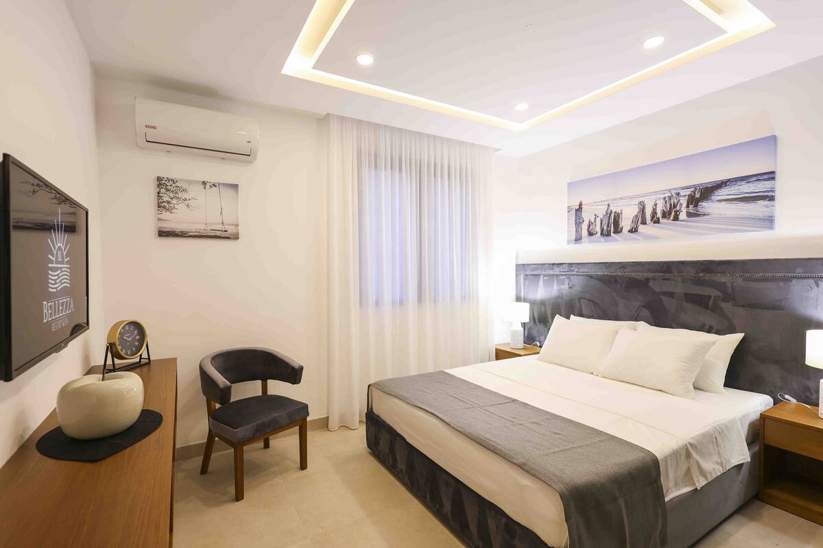 Une chambre d’hôtel moderne dotée d’un grand lit, d’un téléviseur à écran plat, d’un bureau avec une chaise et d’un tableau au mur.