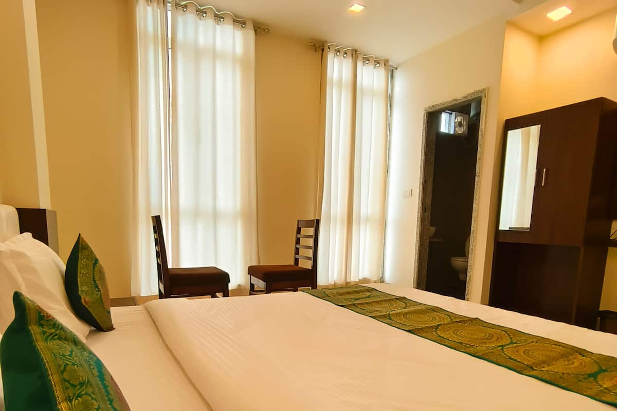 Una habitación de hotel con una cama grande, una silla, un escritorio y un armario.