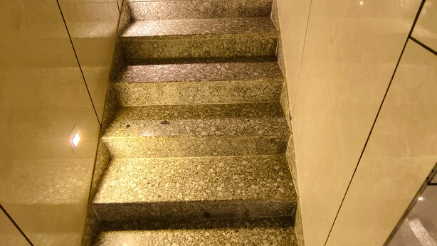 Un escalier avec des marches en granit et des murs blancs.