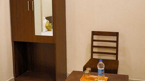 Une pièce comprenant une armoire en bois, une chaise et une petite table sur laquelle se trouve un plateau avec une bouteille et des verres.