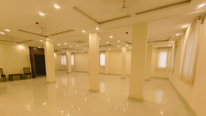 Une chambre d’hôtel spacieuse et bien éclairée, dotée d’un plancher ciré, de grandes fenêtres avec des rideaux et d’un coin salon avec des chaises et un banc.