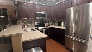 A modern kitchen with dark wooden cabinets, stainless steel appliances, and a central island with a sink.
