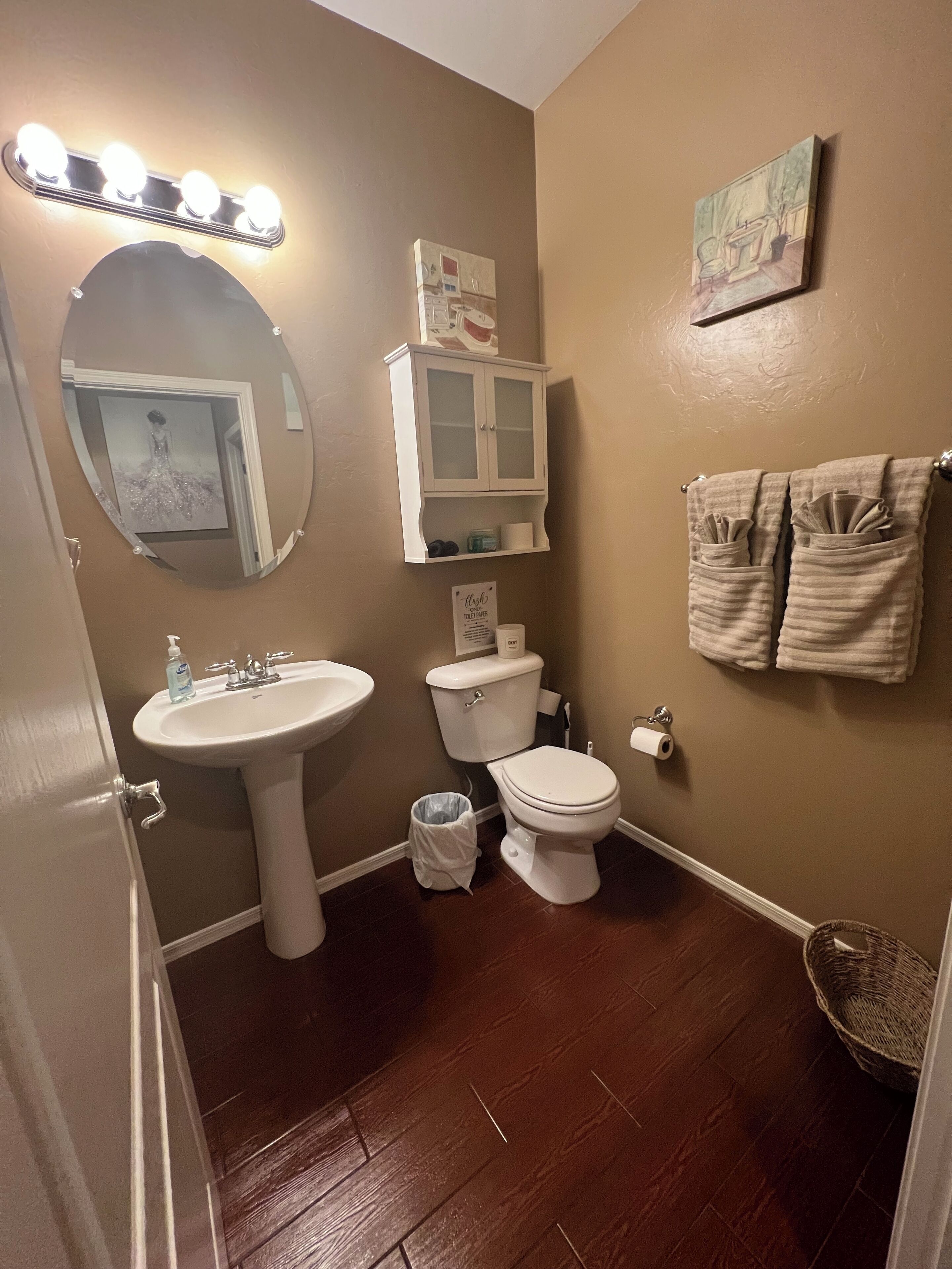 Een badkamer met een wastafel, spiegel, toilet en een kast.