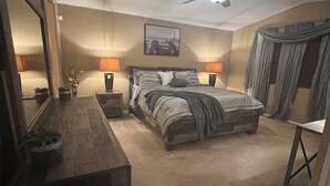 A bedroom with a bed, a ceiling fan, a nightstand, a dresser, and a mirror.