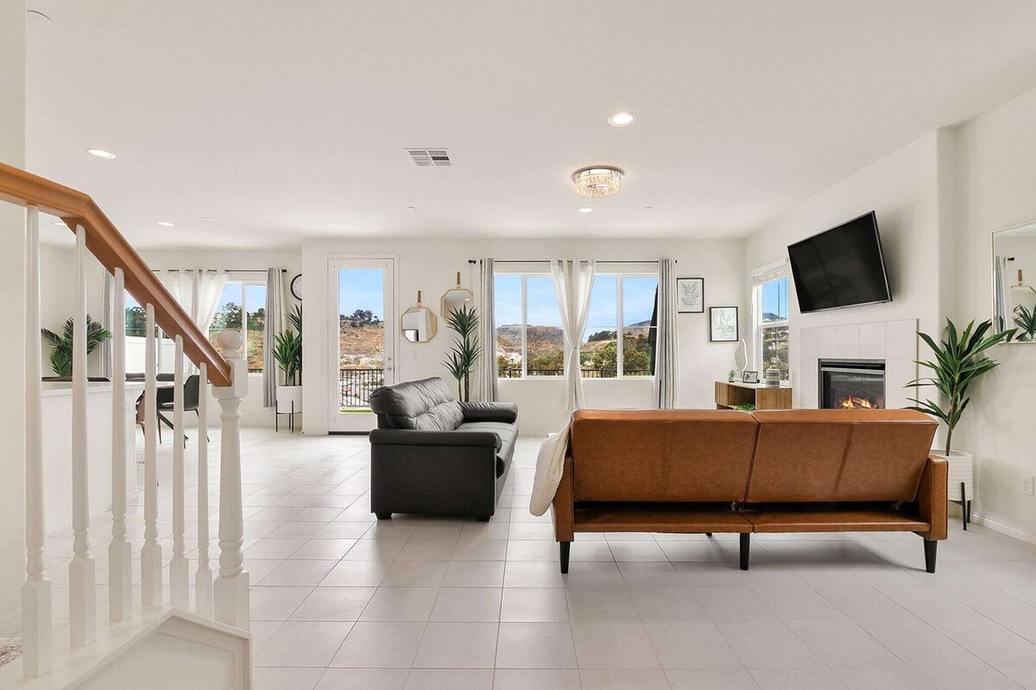 A spacious living room with a staircase, a fireplace, and large windows.