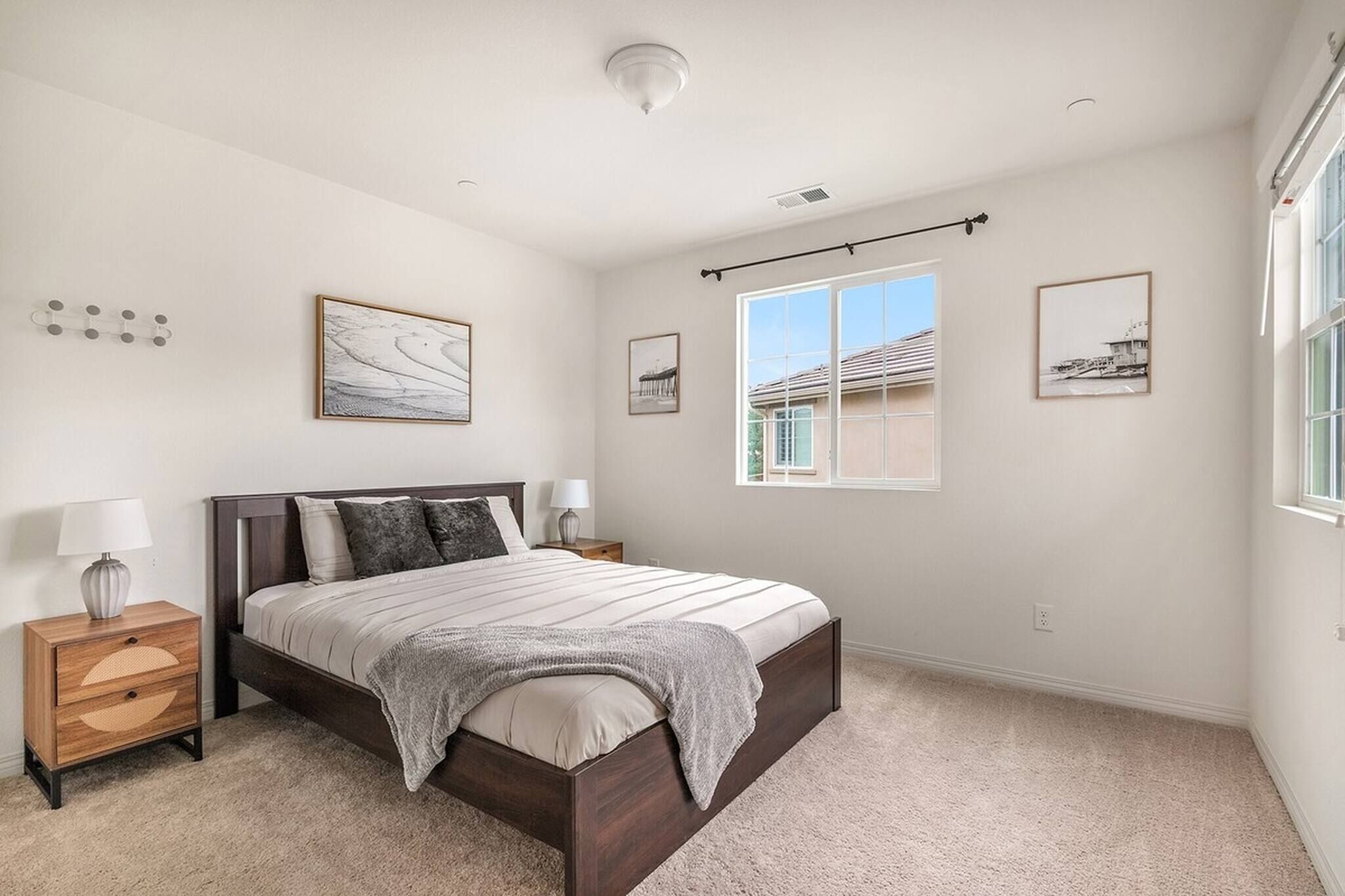 A bedroom with a bed, nightstands, a window, and wall-mounted artwork.