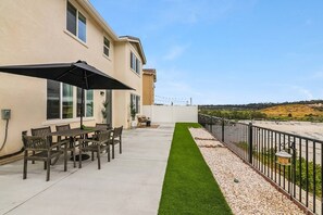 Un patio con mesa y sillas, un pequeño rincón para sentarse y vistas a un paisaje montañoso.