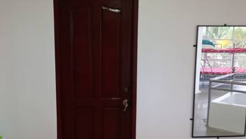 Une pièce dotée d’une porte en bois et d’un grand miroir qui reflète un balcon orné d’une balustrade en métal et d’une nappe à motifs rouges et blancs.