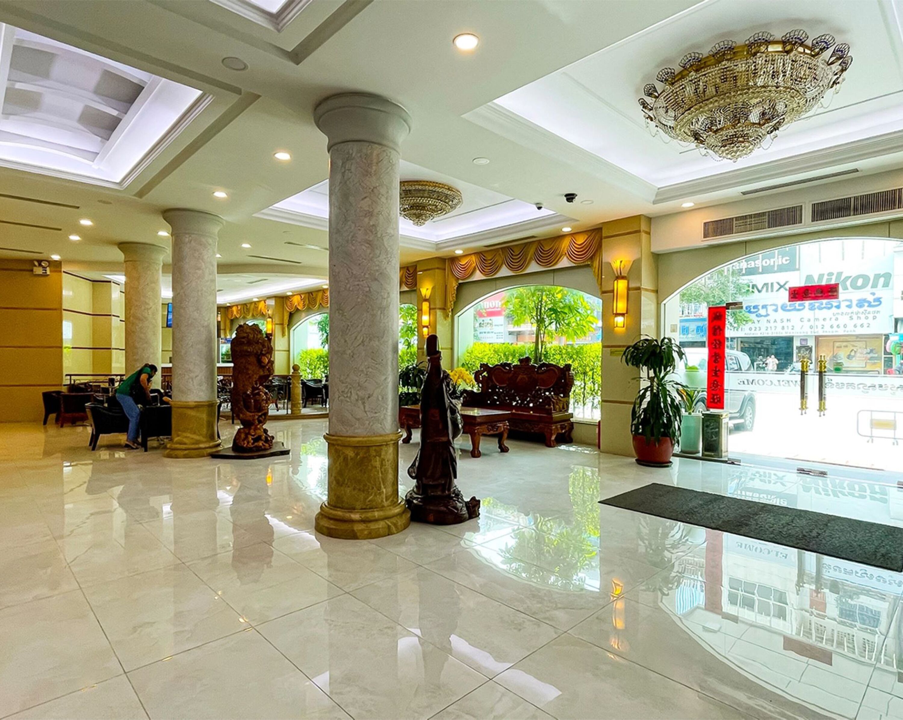 A spacious lobby with marble columns, a chandelier, and a seating area.