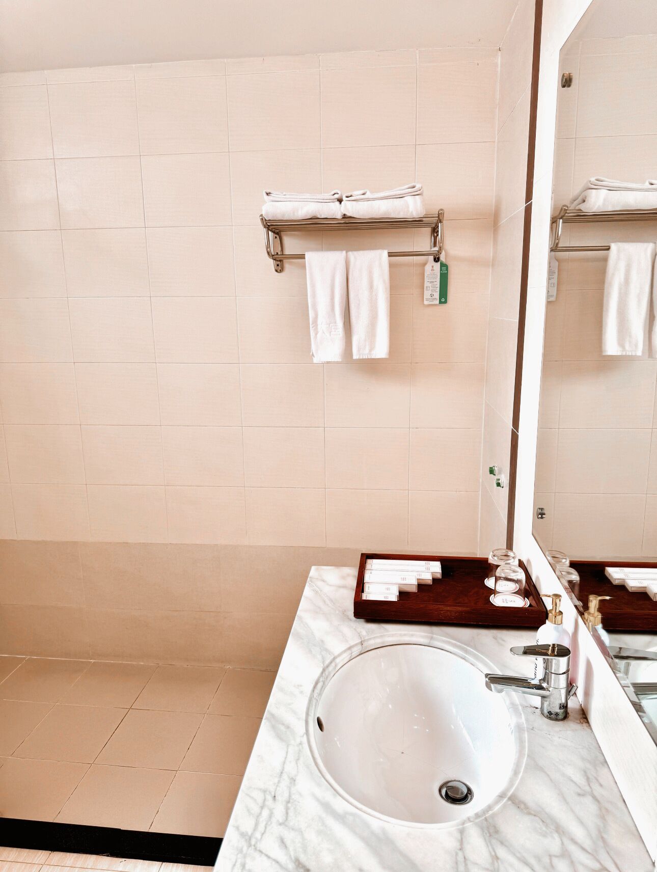 A bathroom with a marble sink, a mirror, and a towel rack with folded towels.